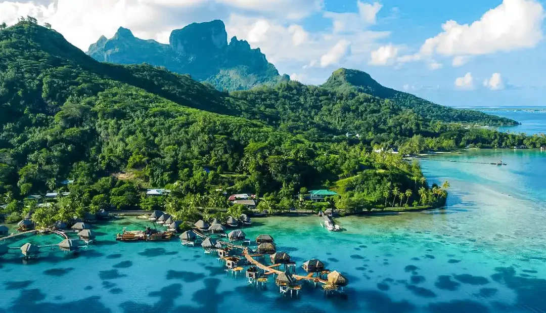 Laguna turchese con bungalow sull’acqua e montagne tropicali in Polinesia Francese