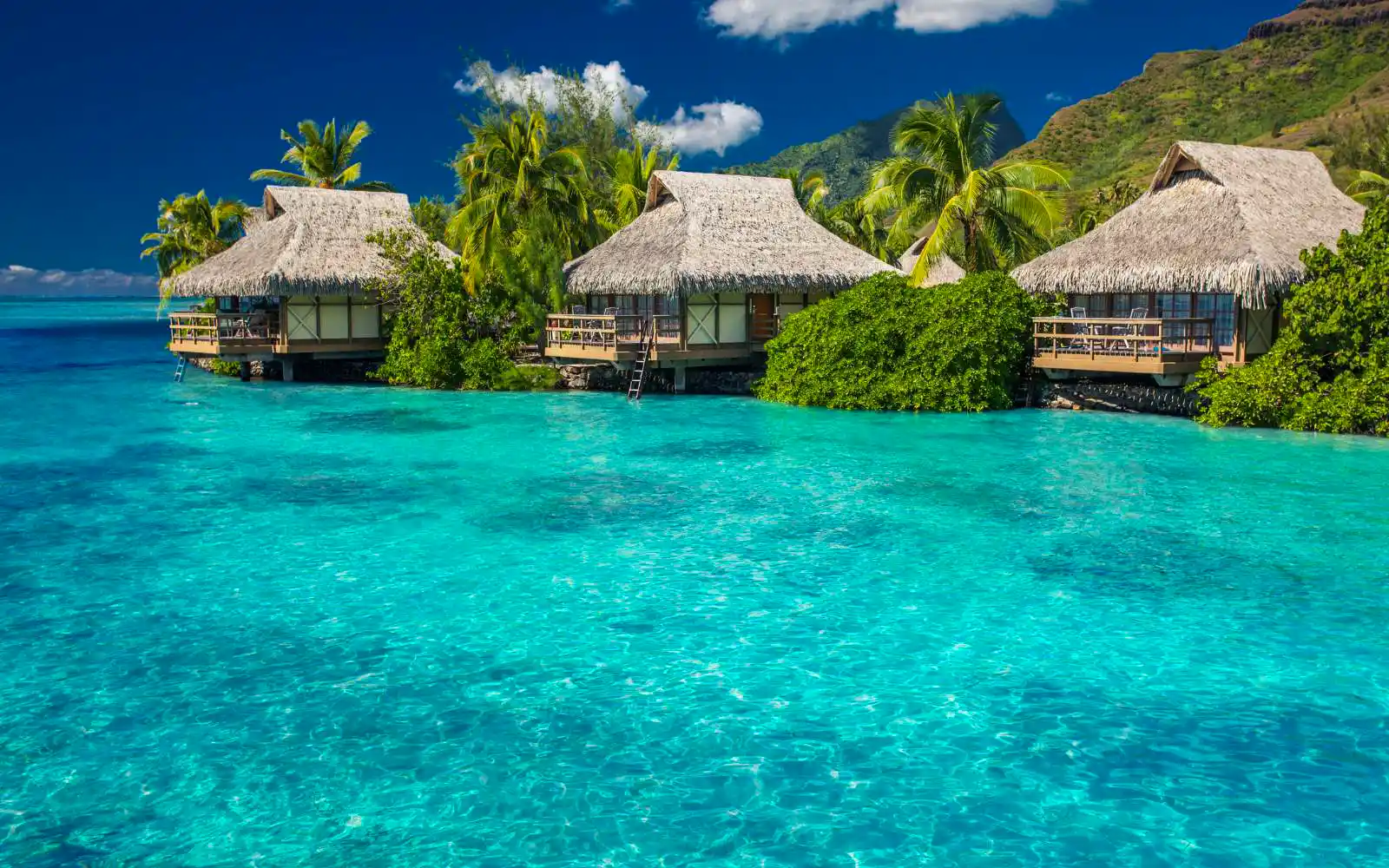 Bungalow sull'acqua a Moorea con laguna cristallina e montagne vulcaniche all'orizzonte