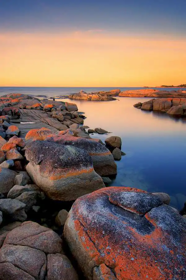 Costa selvaggia della Tasmania con rocce, oceano e luce dorata al tramonto